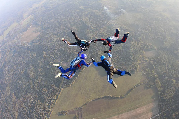 A team of four skydivers is training in the sky.