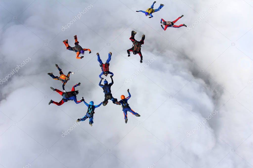 Skydivers are training in the sky above white clouds.