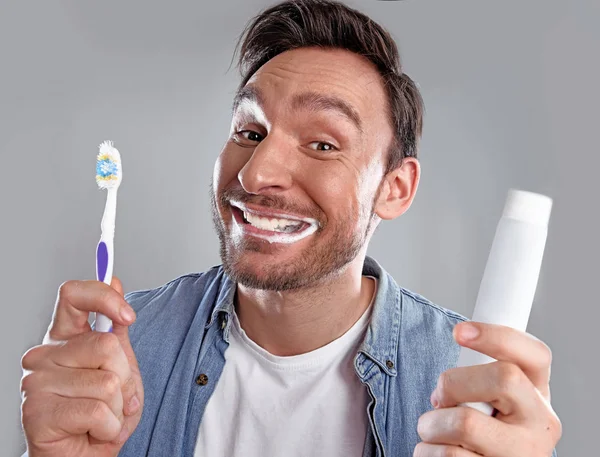 Handsome funny bearded man in whit shirt is obsessed about health of his teeth he cleaned them hard with a toothpaste and a tooth brush and now he is happy