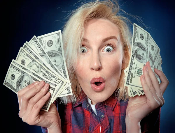 Beautiful young blonde is a lucky winner, she is holding a pile of money, she is surprised and can\'t believe it, she is happy to win one million dollar jackpot, now she is rich.