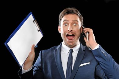 Yakışıklı zeki işadamı bir klasik ofis takım elbise ve kravat bir telefonda konuşmak ve onun bu işle onun Pano holding ile komik korkmuş yüz çalışkan siyah bir arka plan üzerinde izole