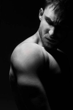 Düşük ışıkta poz içinde büyük ve güçlü kas adam. Fitness modeli veya onun pazı, omuz ve göğüs gösteren bir eğitmen. Kızgın mma savaşçı veya bir vücut geliştirmeci kıç tekmelemeye hazır.