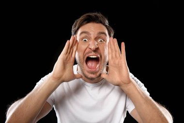 Beyaz t gömlek siyah veya beyaz arka plan üzerinde izole çığlık içinde yakışıklı genç adam. Elleri havada ile bağıran adam. Stresli futbol Fan bağırıyor ve takımı için tezahürat. Farklı duygular, üzüntü, depresyon, sevinç ve gülümseme adam gösterir