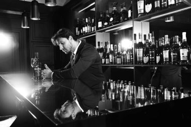 Genç ve yakışıklı adam rahat barda oturan bir cam ve bir şişe ile karşı. Alkolik bir şişe çevresindeki barda. Seksi bir görünüme sahip güzel barmen