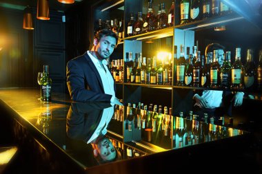 Genç ve yakışıklı adam rahat barda oturan bir cam ve bir şişe ile karşı. Alkolik bir şişe çevresindeki barda. Seksi bir görünüme sahip güzel barmen