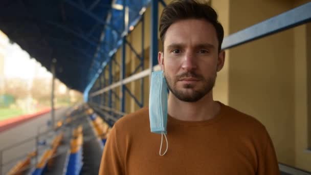 Een Man Met Een Chirurgisch Masker Die Een Leeg Stadion — Stockvideo