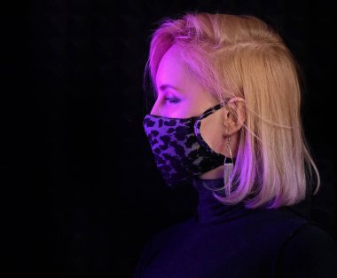 Neon ışıklı kadın Coronavirus 'a karşı cerrahi maske takarak poz veriyor, enfeksiyon kapmış kız covid-19 salgınından korkuyor, maske takıyor, siyah arka planda gizlenmiş hasta var.