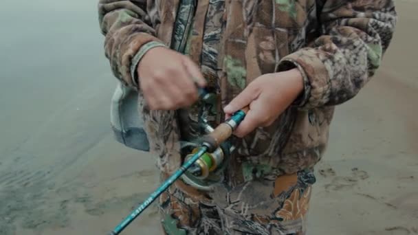 川の土手にスピニング リールをねじれ漁師の手のクローズ アップの手のクローズ アップ — ストック動画