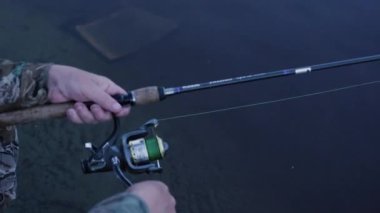 Eller üzerinde nehir kıyısında bir iplik makara büküm bir balıkçının el Close-up Close-Up