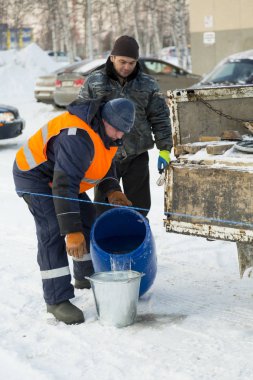 İşçi fıçıdan kovaya su döker.