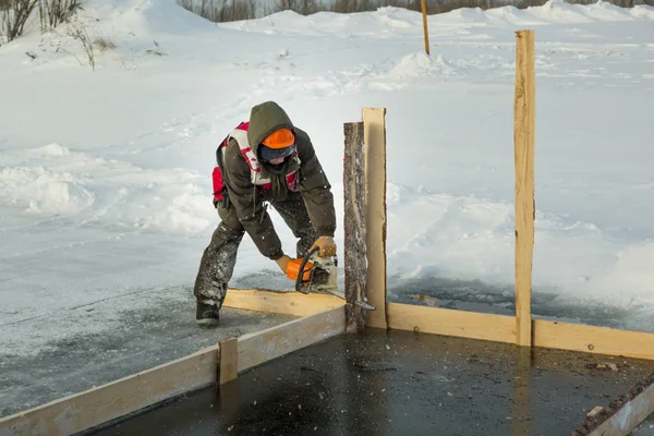 Worker with a chainsaw in the hands of an ice hole — Stock Image Worker with a chainsaw in the hands of an ice hole Stock Image