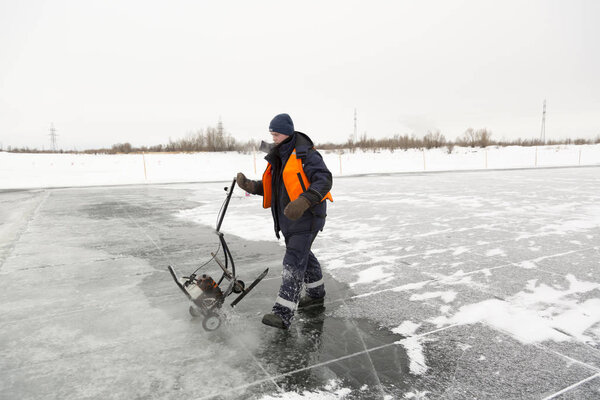 Worker cuts out ice blocks in size on the ice of a frozen lake