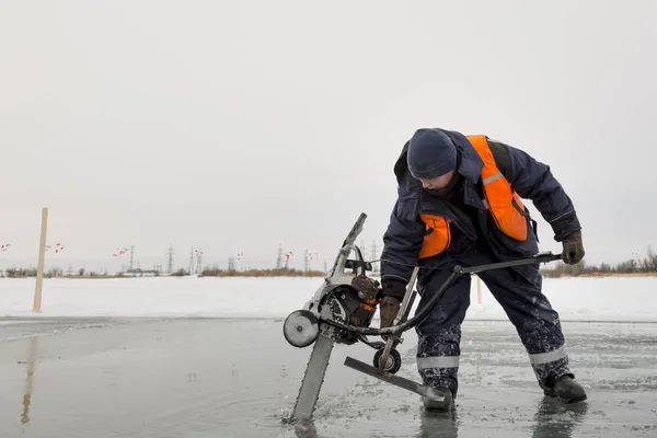 Trabajador corta bloques de hielo en tamaño en el hielo de un lago congelado —  Fotos de Stock