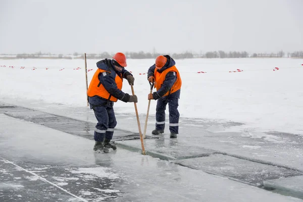 Arbetare forsränning isblock längs en kanal utskuren av en frusen sjö — Stockfoto