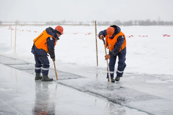 Arbetare forsränning isblock längs en kanal utskuren av en frusen sjö — Stockfoto