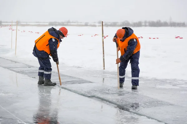 Arbetare forsränning isblock längs en kanal utskuren av en frusen sjö — Stockfoto