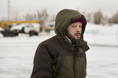 Kapüşonlu yeşil ceketli bir işçinin portresi