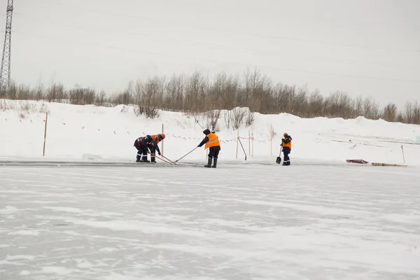 Workers rafting ice blocks along a channel cut out by a frozen lake
