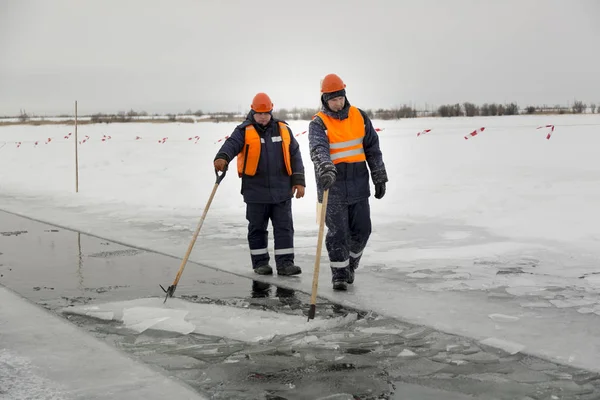 Arbetare forsränning isblock längs en kanal utskuren av en frusen sjö — Stockfoto