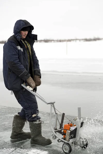 Arbeiter schneidet Eisblöcke vom Eis eines zugefrorenen Sees — Stockfoto