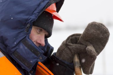 Mavi ceketli ve turuncu yelekli bir montajcının portresi.