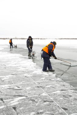 İşçi salları donmuş bir göle oyulmuş bir kanal boyunca buz blokları