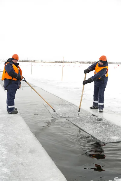 Arbetare forsränning isblock längs en kanal utskuren av en frusen sjö — Stockfoto
