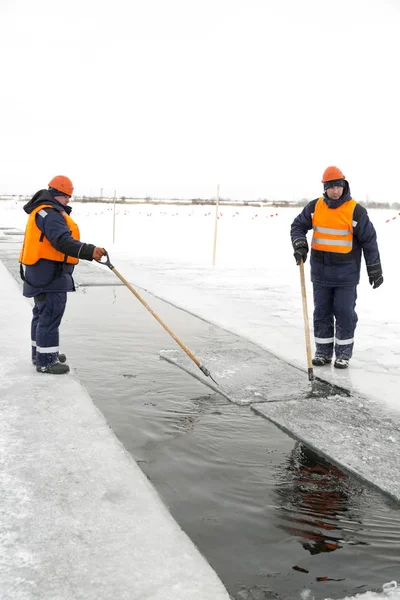 Arbetare forsränning isblock längs en kanal utskuren av en frusen sjö — Stockfoto