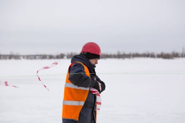 Kurulum alanında turuncu yelekli bir Slinger yürüyor.