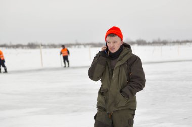 Donmuş bir gölün buzunda cep telefonuyla yürüyen bir işçi.