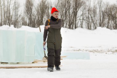 Kırmızı örgü şapkalı işçi toplantı alanında yürüyor.