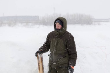 Kışlık işçi tulumuyla elinde tahtasıyla.