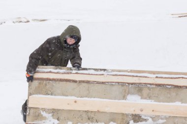 Kışın işçi tulumuyla ahşap bir kalkanı sürüklüyor.
