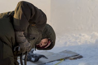 Fitter with steel tongs pulls out ice block