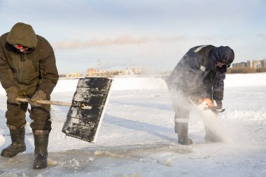 Worker cuts the ice with a gasoline saw