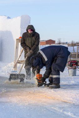 Worker cuts the ice with a gasoline saw