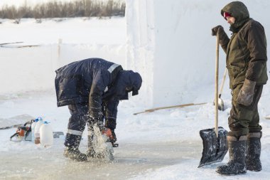 Worker cuts the ice with a gasoline saw