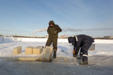 Worker cuts the ice with a gasoline saw