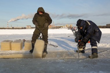 Worker cuts the ice with a gasoline saw
