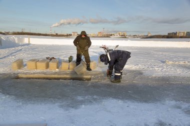 Worker cuts the ice with a gasoline saw