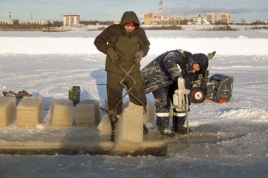 Worker cuts the ice with a gasoline saw