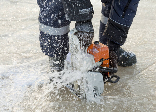 Hands of a fitter with a chainsaw at a construction site