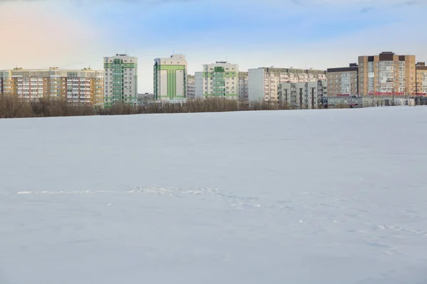 Landschaft eines gefrorenen Flusses vor dem Hintergrund des Stadtdamms — Stockfoto