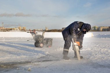 Worker cuts the ice with a gasoline saw