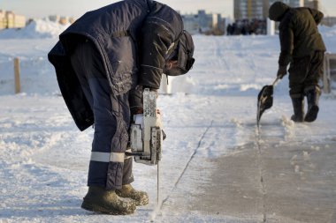Worker cuts the ice with a gasoline saw