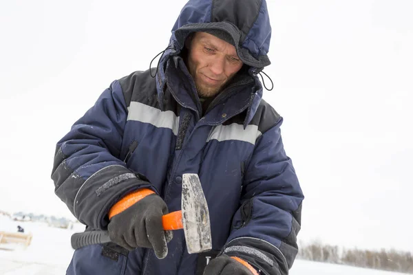 Arbeiter im Winteranzug mit Hammer in der Hand — Stockfoto