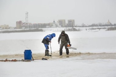 Worker cuts the ice with a gasoline saw