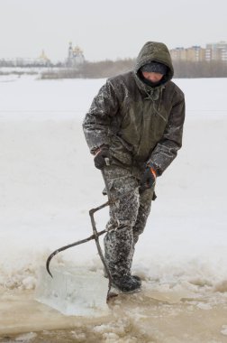 Fitter with steel tongs pulls out ice block