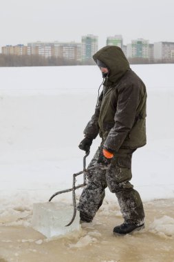 Fitter with steel tongs pulls out ice block