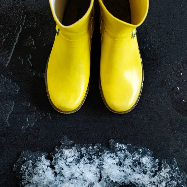 Yellow Rubber Boots Front Snow Melting Black Background — Stock Photo, Image